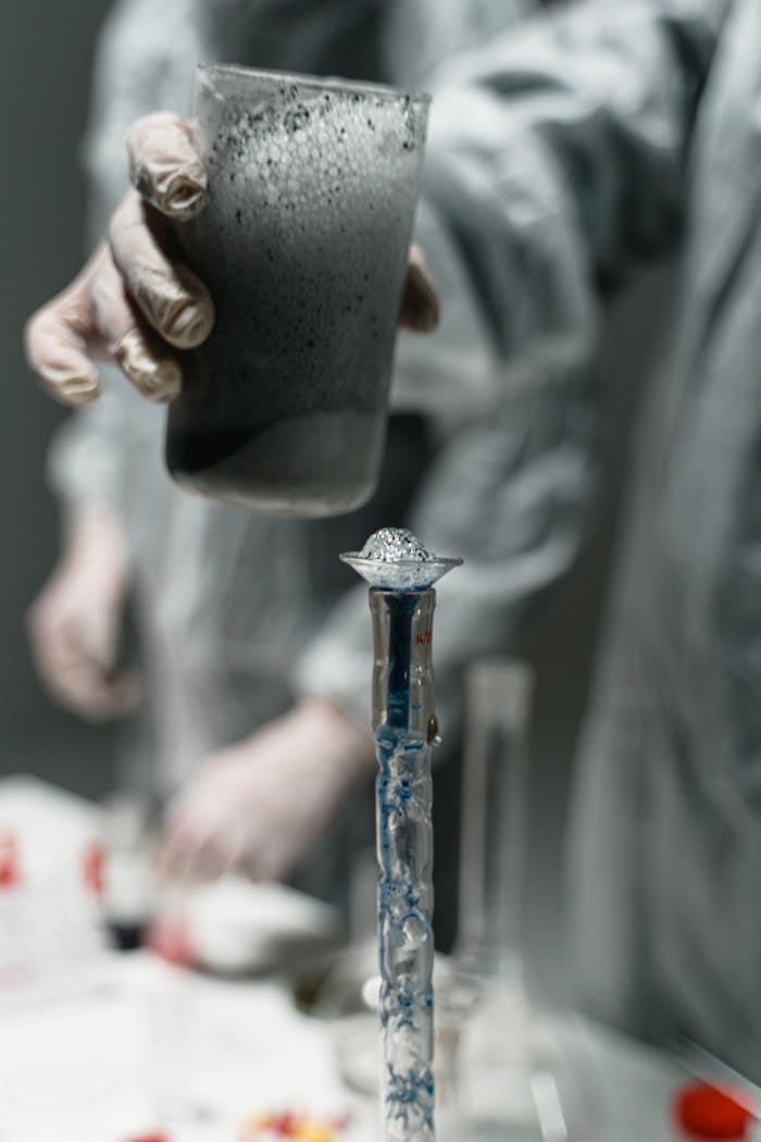 Lab experiment with liquid pouring into test tube, scientific research setting.