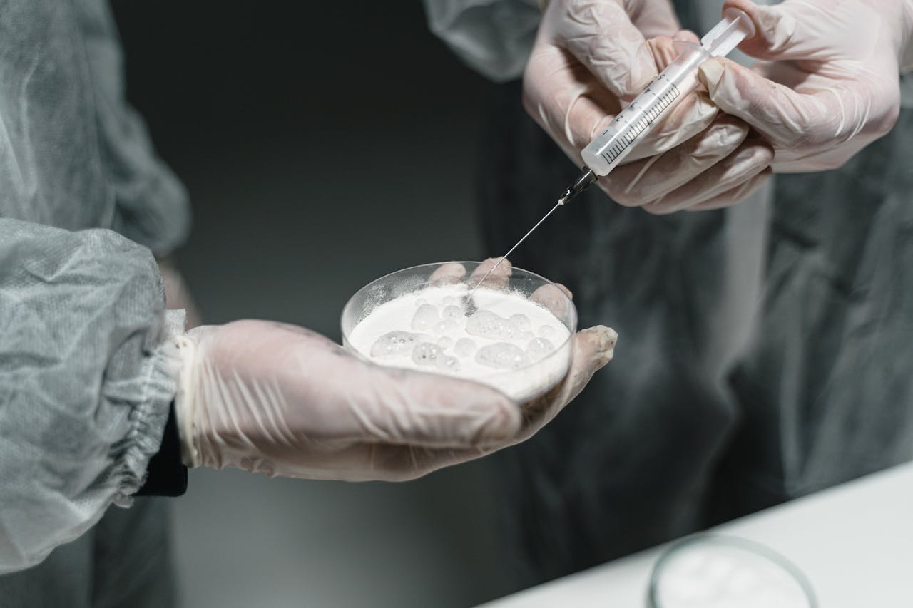 Researchers conducting a scientific experiment with a syringe and petri dish in a lab setting.