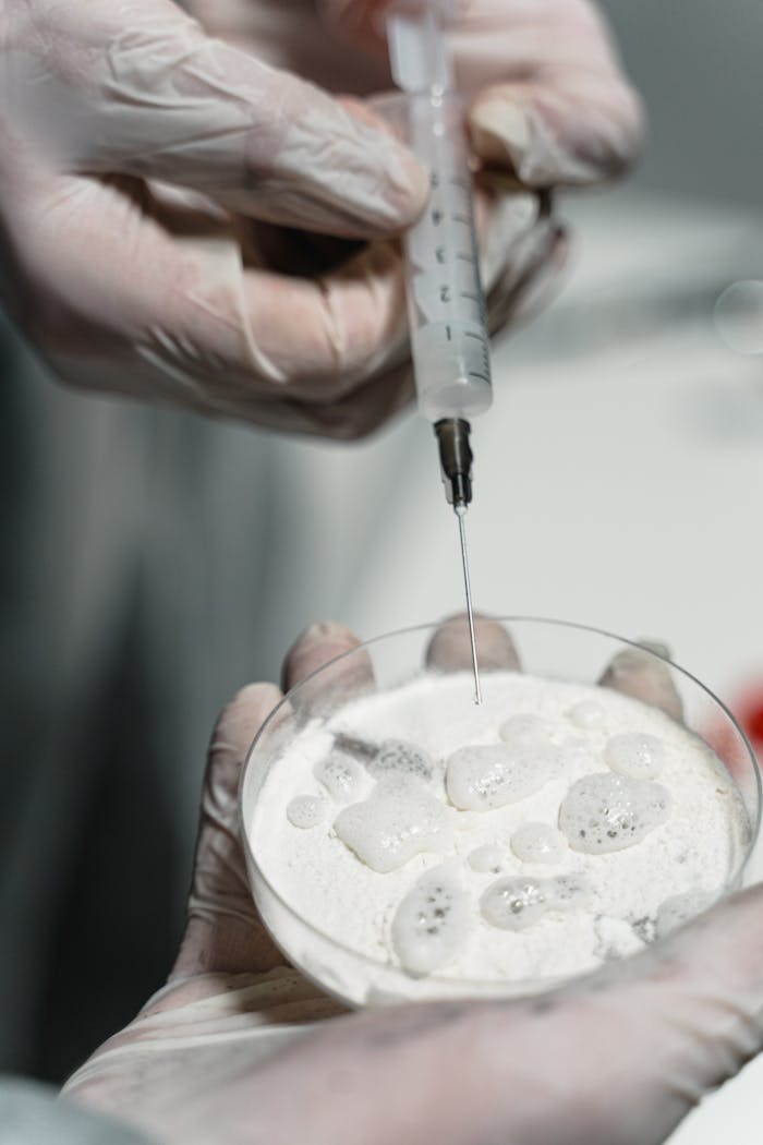 Close-up of hands in gloves using syringe in laboratory setting.