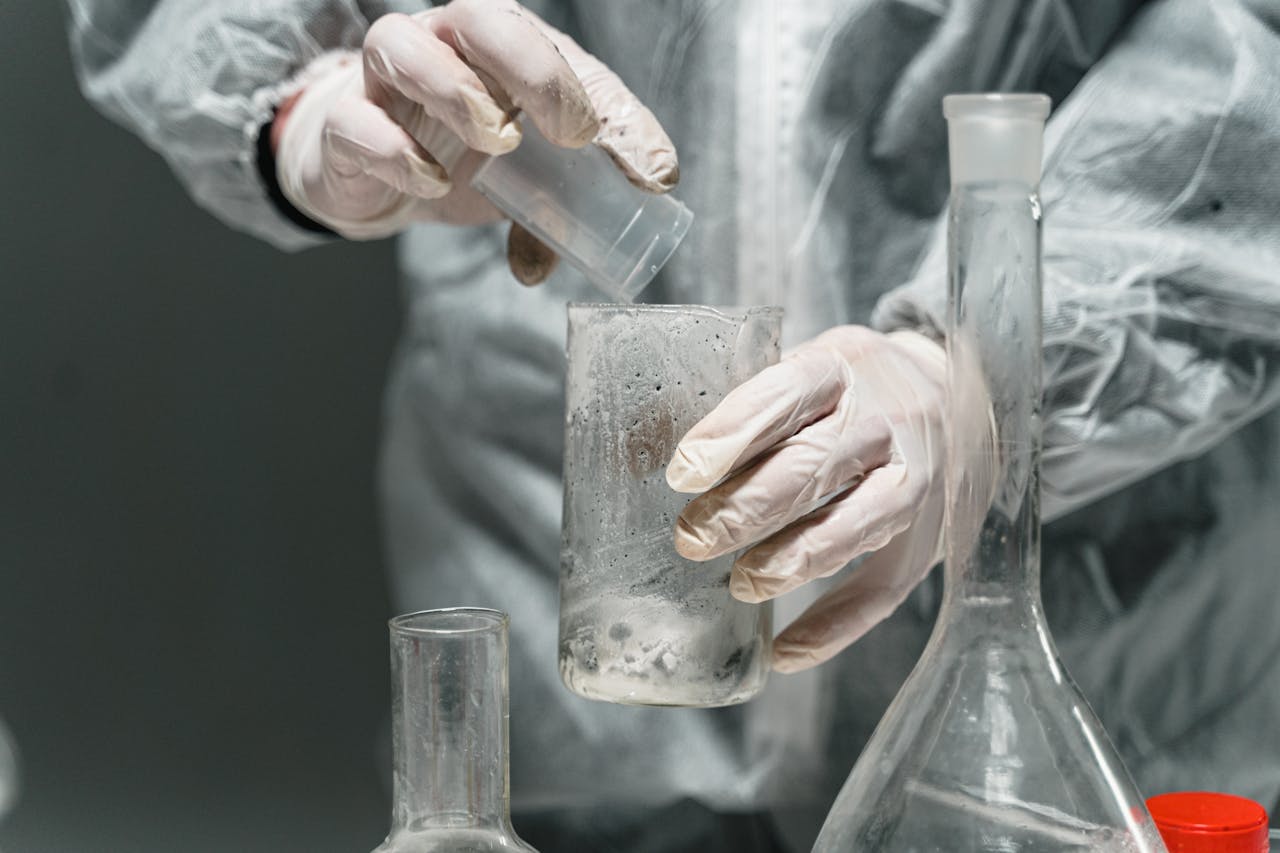 Scientist in a lab coat working with glassware and chemicals for research in a laboratory setting.